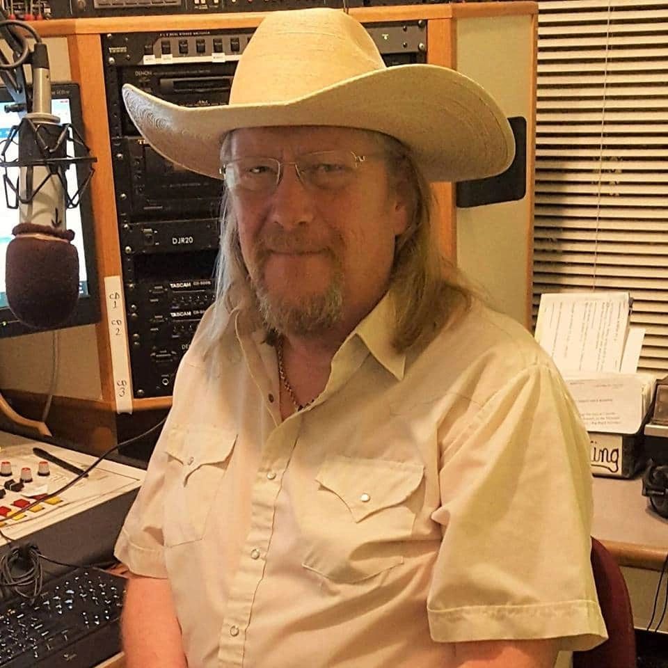 Man wearing a cowboy hat and glasses in a radio studio.